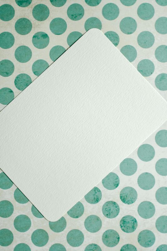 Blank card on green polka dot surface, perfect for mockups and designs.
