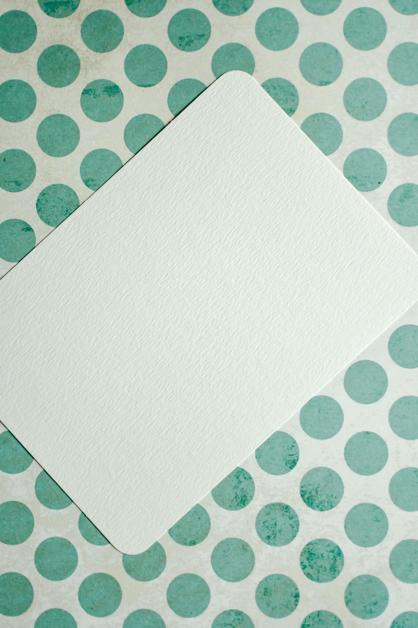 Blank card on green polka dot surface, perfect for mockups and designs.