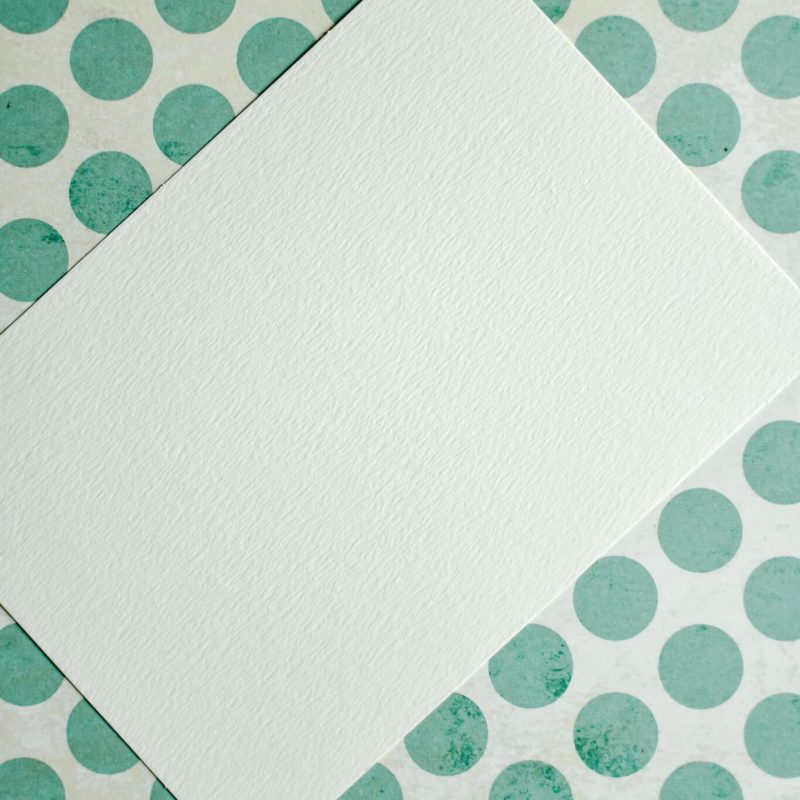Blank card on green polka dot surface, perfect for mockups and designs.
